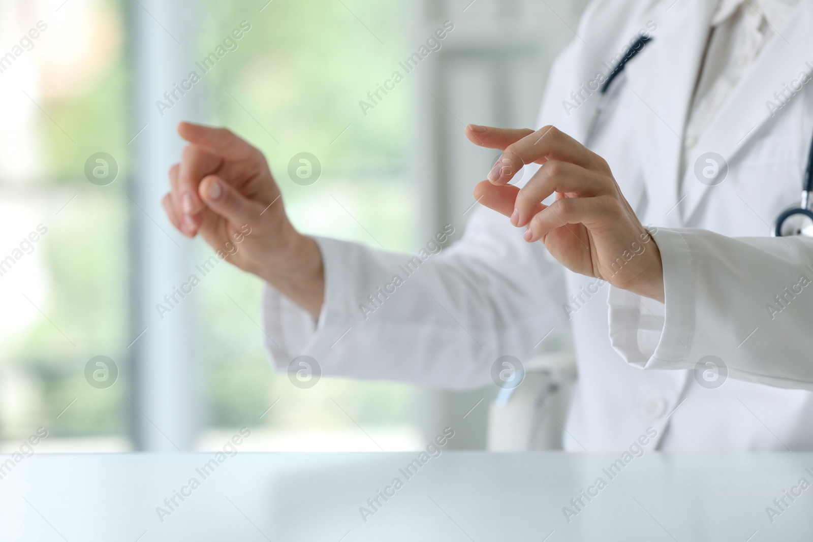 Photo of Doctor with stethoscope holding something at table in clinic, closeup