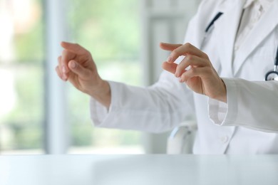 Doctor with stethoscope holding something at table in clinic, closeup