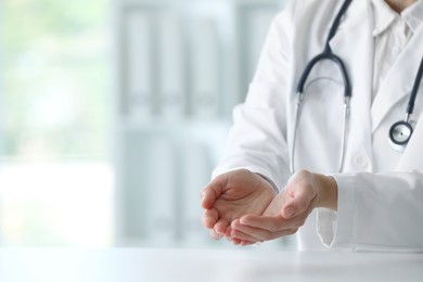 Photo of Doctor with stethoscope holding something at table in clinic, closeup. Space for text