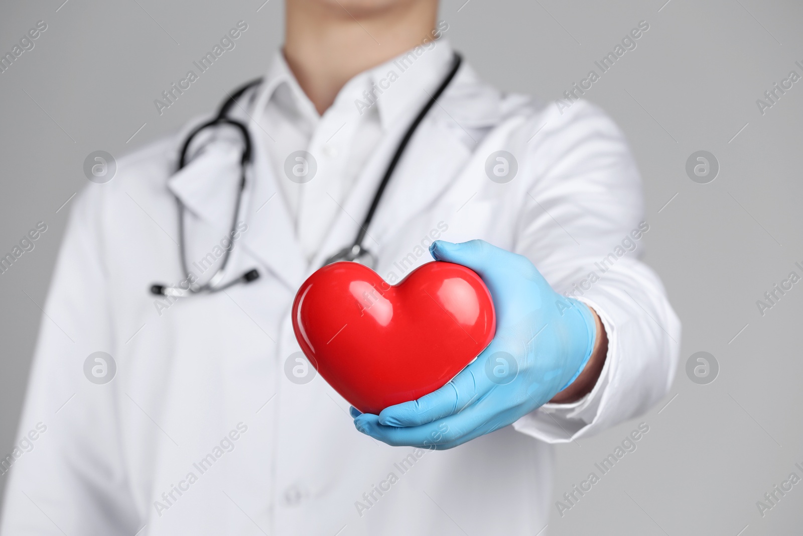 Photo of Doctor with red heart on grey background, selective focus