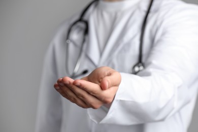 Photo of Doctor holding something on grey background, closeup