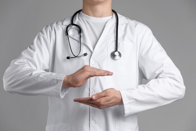 Photo of Doctor holding something on grey background, closeup