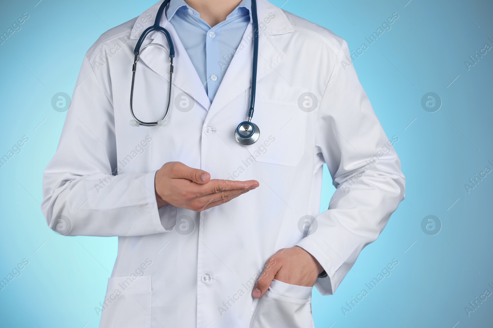 Photo of Doctor holding something on light blue background, closeup