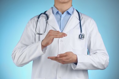 Doctor holding something on light blue background, closeup