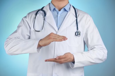 Photo of Doctor holding something on light blue background, closeup