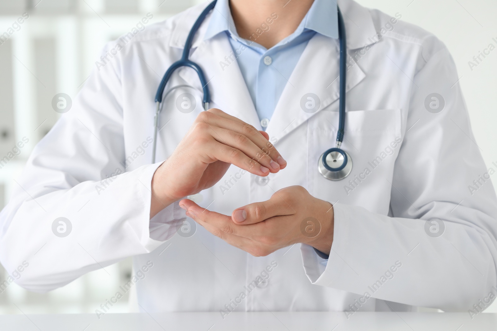 Photo of Doctor holding something at white table in clinic, selective focus