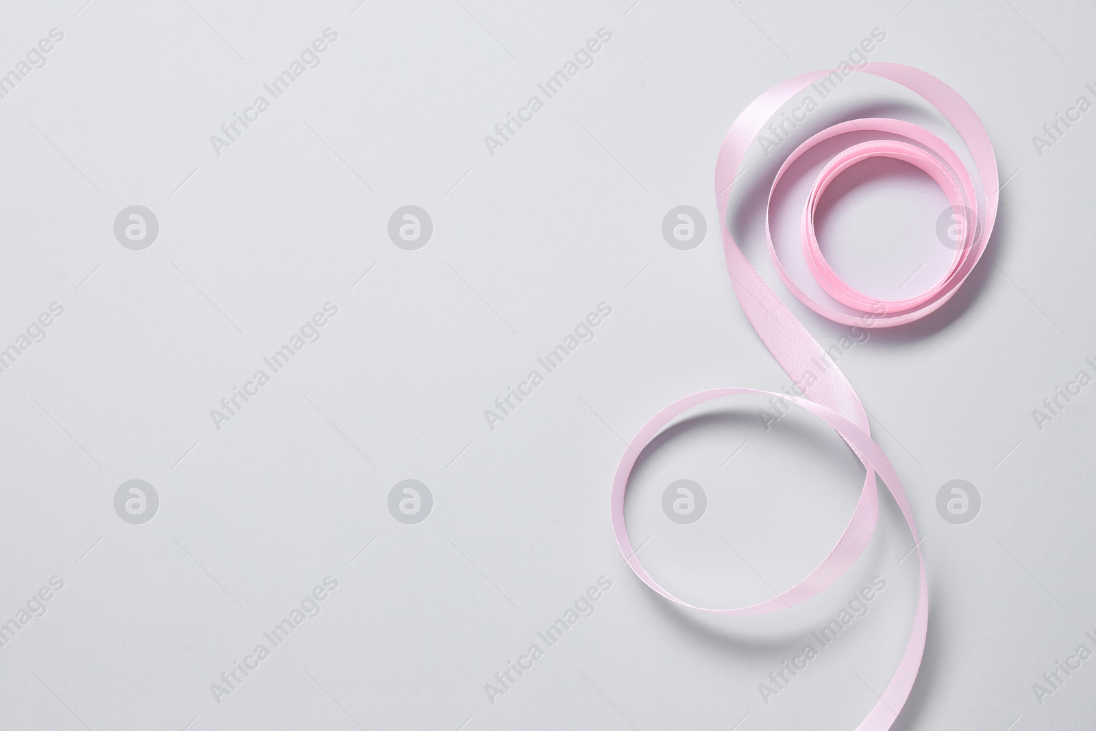 Photo of One beautiful pink ribbon on white background, top view. Space for text