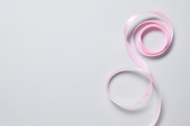 Photo of One beautiful pink ribbon on white background, top view. Space for text