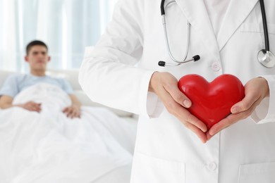 Photo of Doctor holding red heart in clinic, selective focus