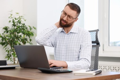 Photo of Man suffering from neck pain in office. Symptom of poor posture
