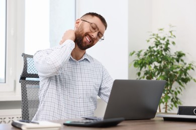 Photo of Man suffering from neck pain in office. Symptom of poor posture
