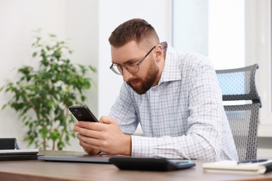Photo of Man with poor posture using smartphone in office