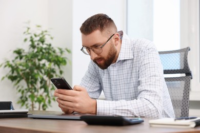 Man with poor posture using smartphone in office