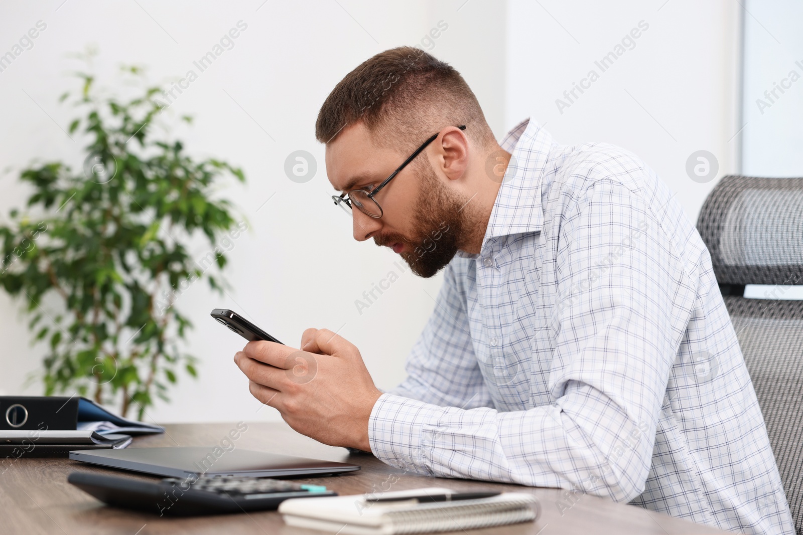 Photo of Man with poor posture using smartphone in office