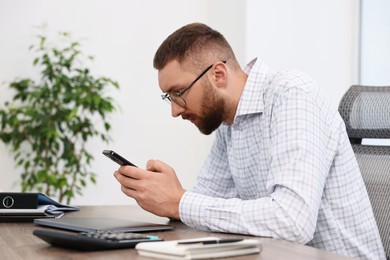 Man with poor posture using smartphone in office