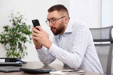 Man with poor posture using smartphone in office