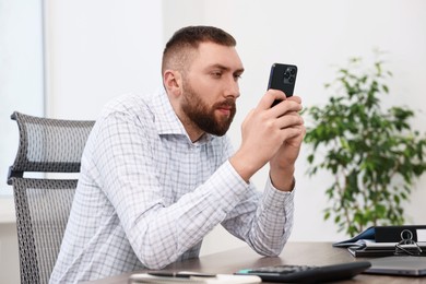 Photo of Man with poor posture using smartphone in office