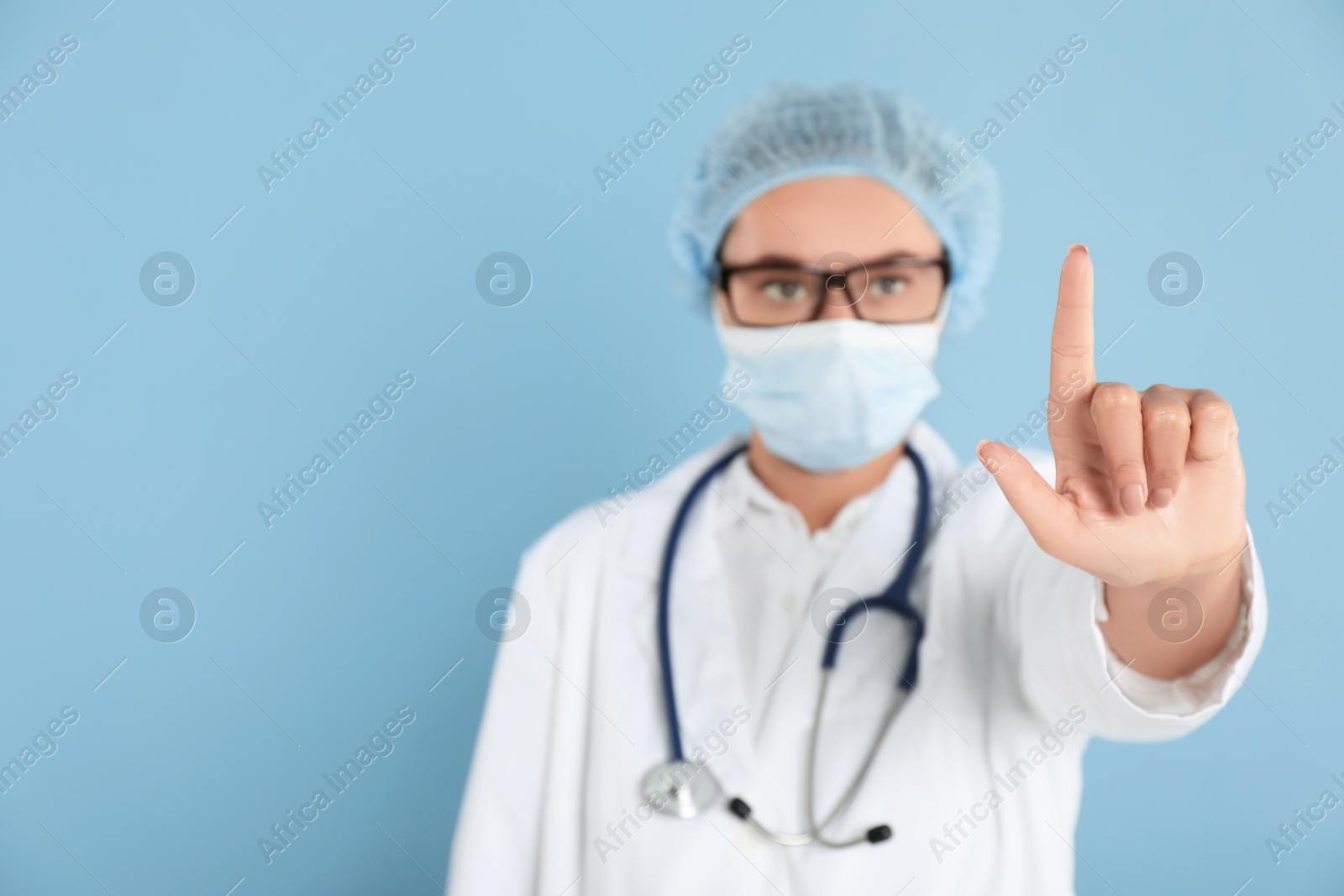 Photo of Doctor pointing at something on light blue background, selective focus. Space for text