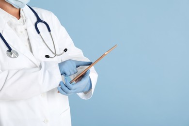 Photo of Doctor with tablet on light blue background, closeup view. Space for text