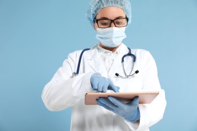 Photo of Doctor with tablet on light blue background, selective focus