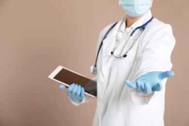 Photo of Doctor with tablet holding something on beige background, closeup