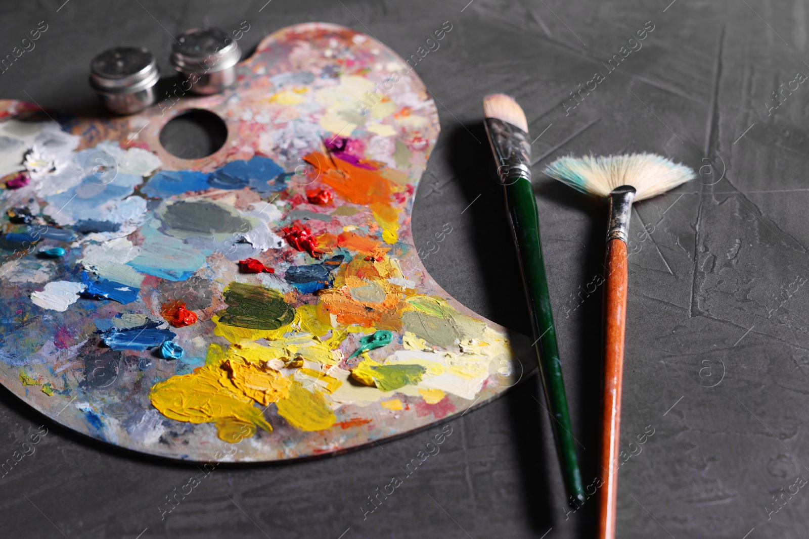 Photo of Artist's palette, brushes and paints on grey table, closeup