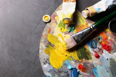 Artist's palette, brush and paints on grey table, flat lay. Space for text