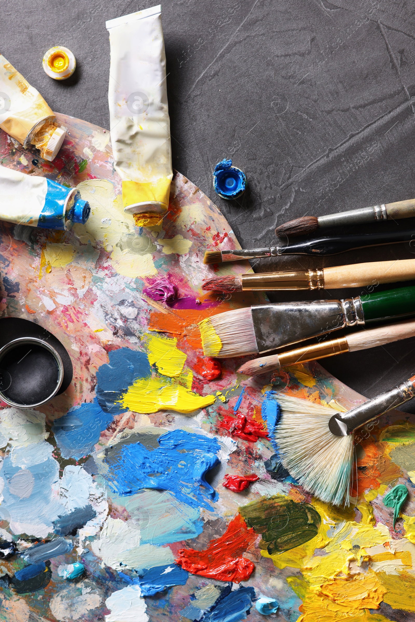 Photo of Artist's palette, brushes and paints on grey table, flat lay