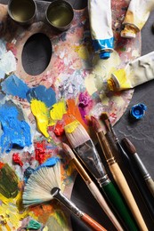 Photo of Artist's palette, brushes and paints on grey table, flat lay