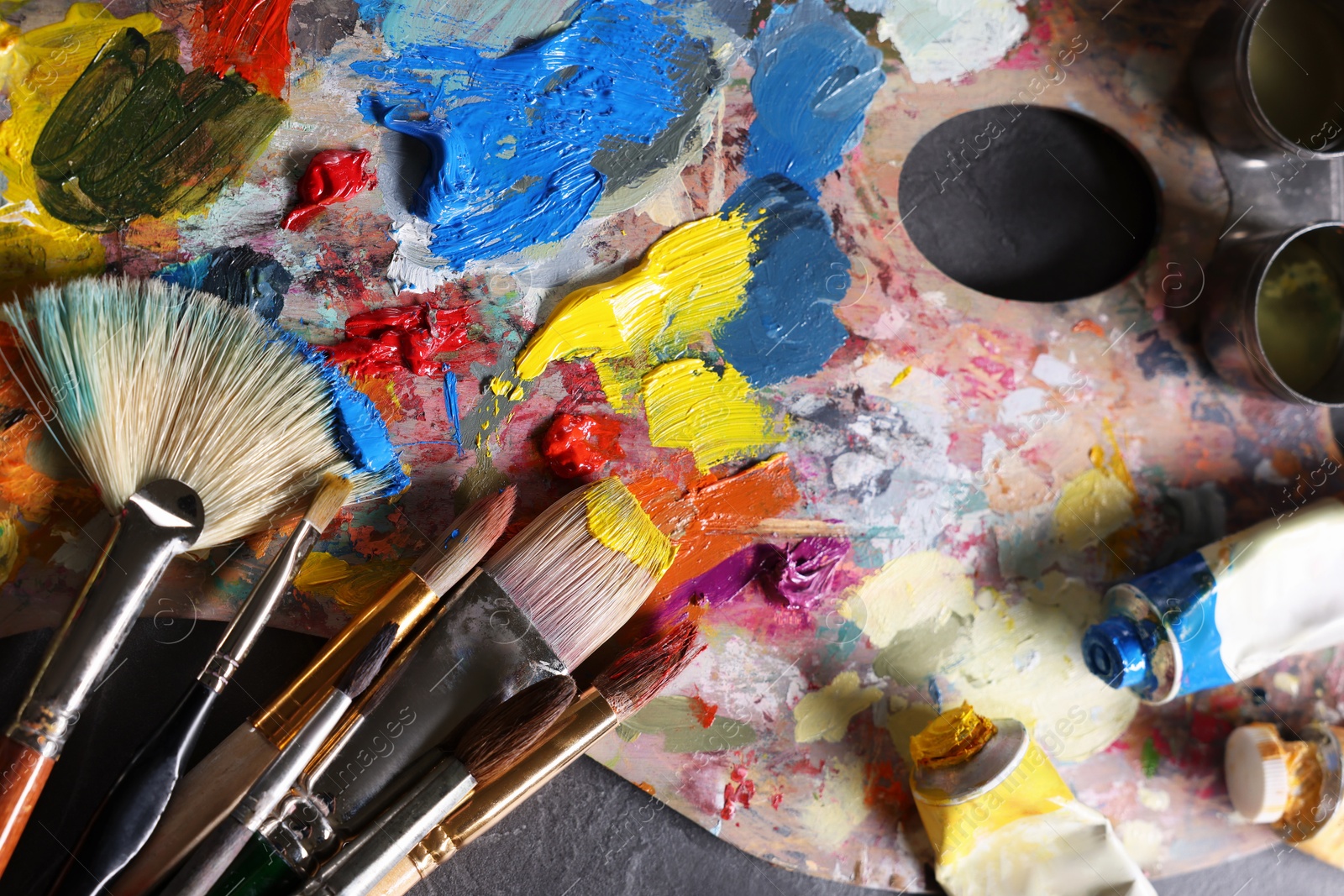 Photo of Artist's palette, brushes and paints on grey table, flat lay