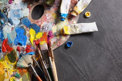 Artist's palette, brushes and paints on grey table, flat lay. Space for text