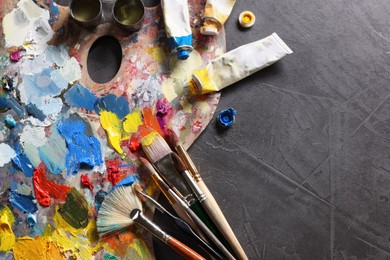 Artist's palette, brushes and paints on grey table, flat lay. Space for text