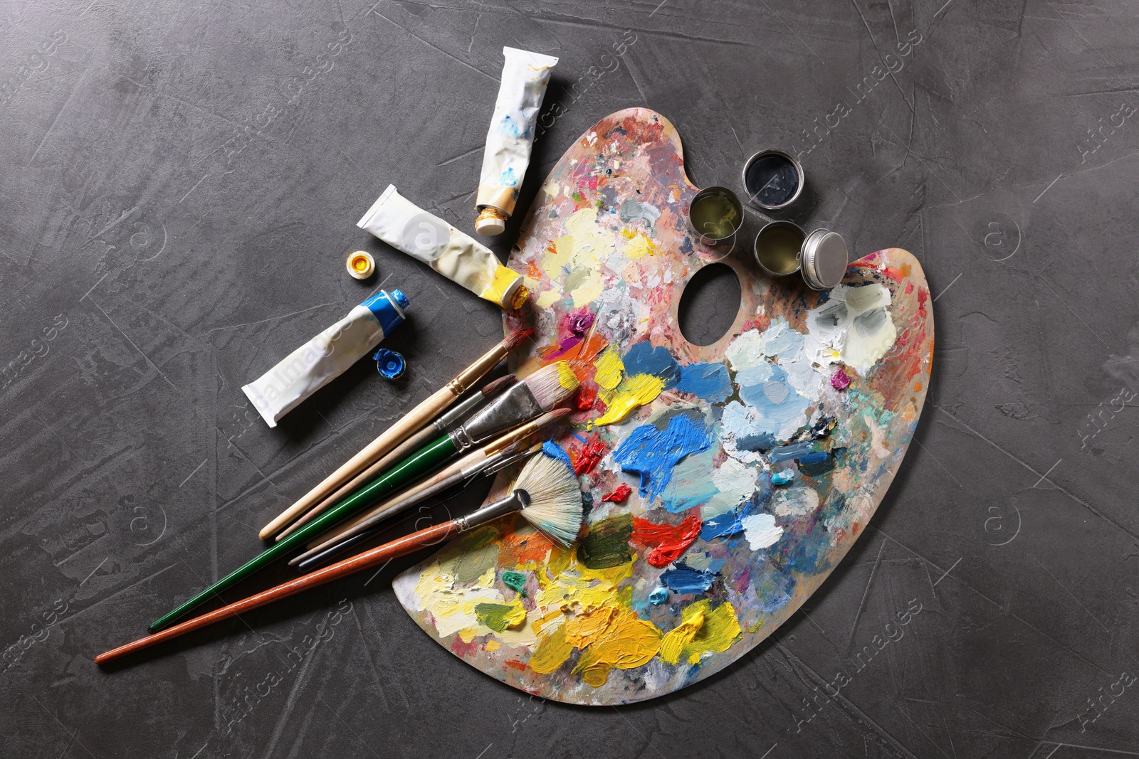 Photo of Artist's palette, brushes and paints on grey table, flat lay