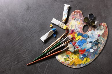 Artist's palette, brushes and paints on grey table, flat lay. Space for text