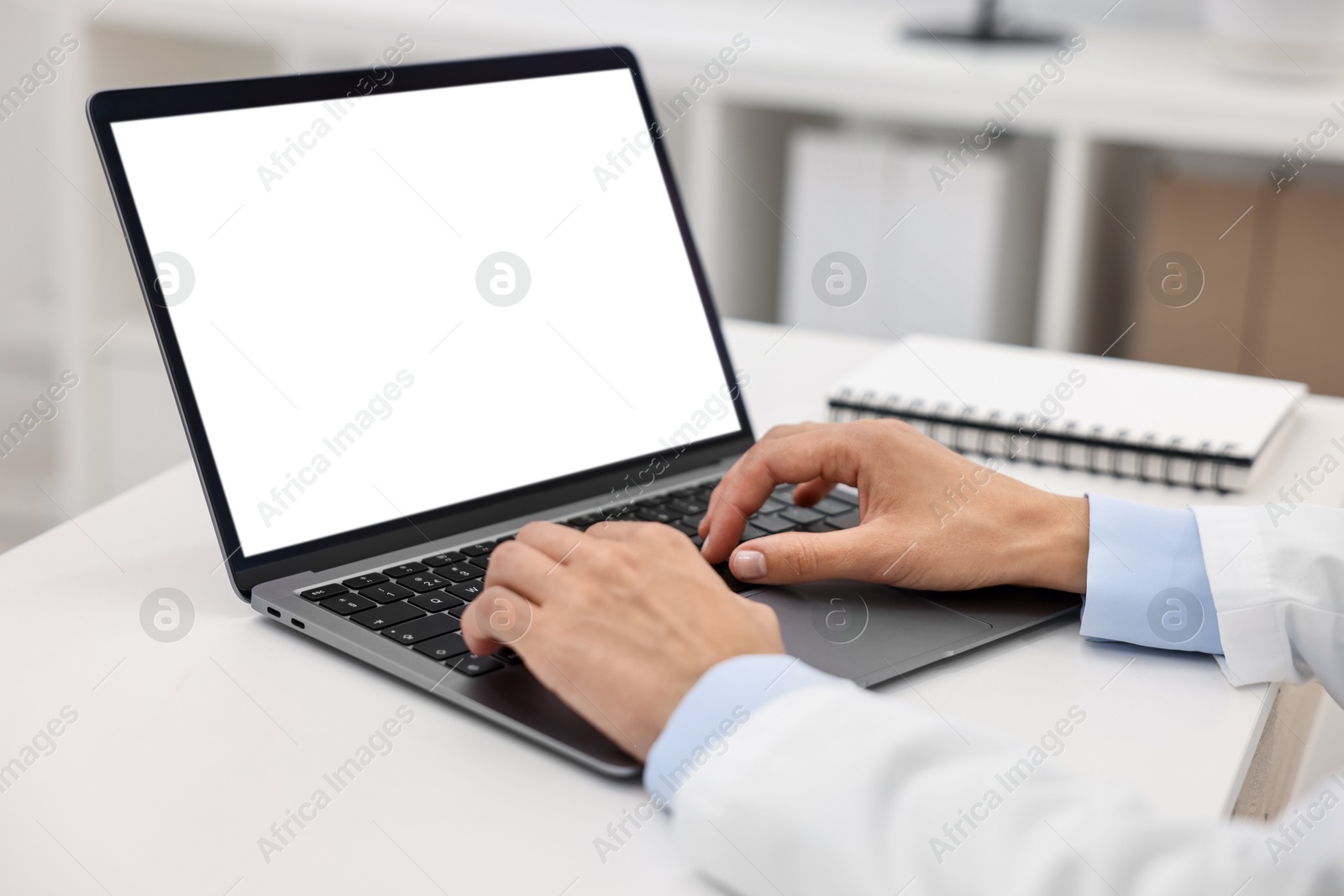 Photo of Doctor using laptop at white table in hospital, closeup