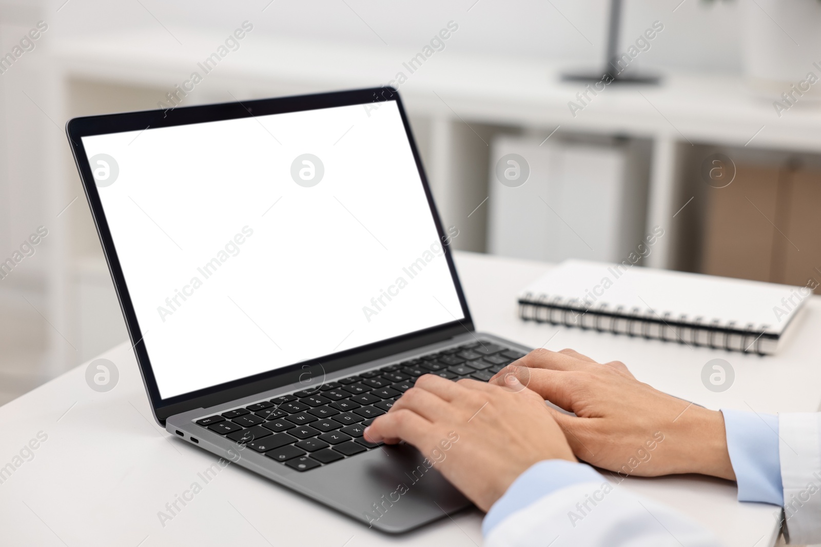 Photo of Doctor using laptop at white table in hospital, closeup