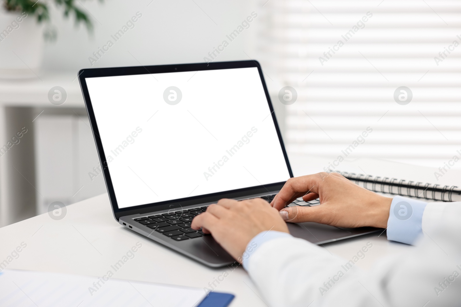 Photo of Doctor using laptop at white table in hospital, closeup