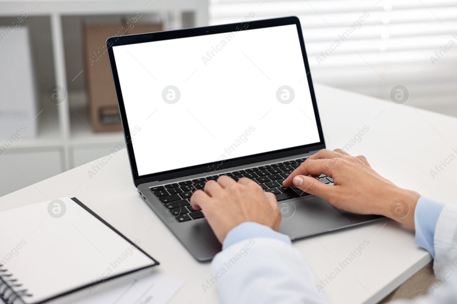 Photo of Doctor using laptop at white table in hospital, closeup