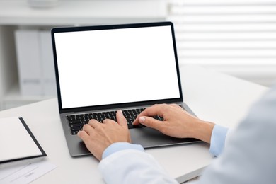 Photo of Doctor using laptop at white table in hospital, closeup