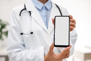 Photo of Doctor showing smartphone with blank screen in hospital, selective focus