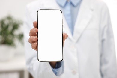 Photo of Doctor showing smartphone with blank screen in hospital, selective focus