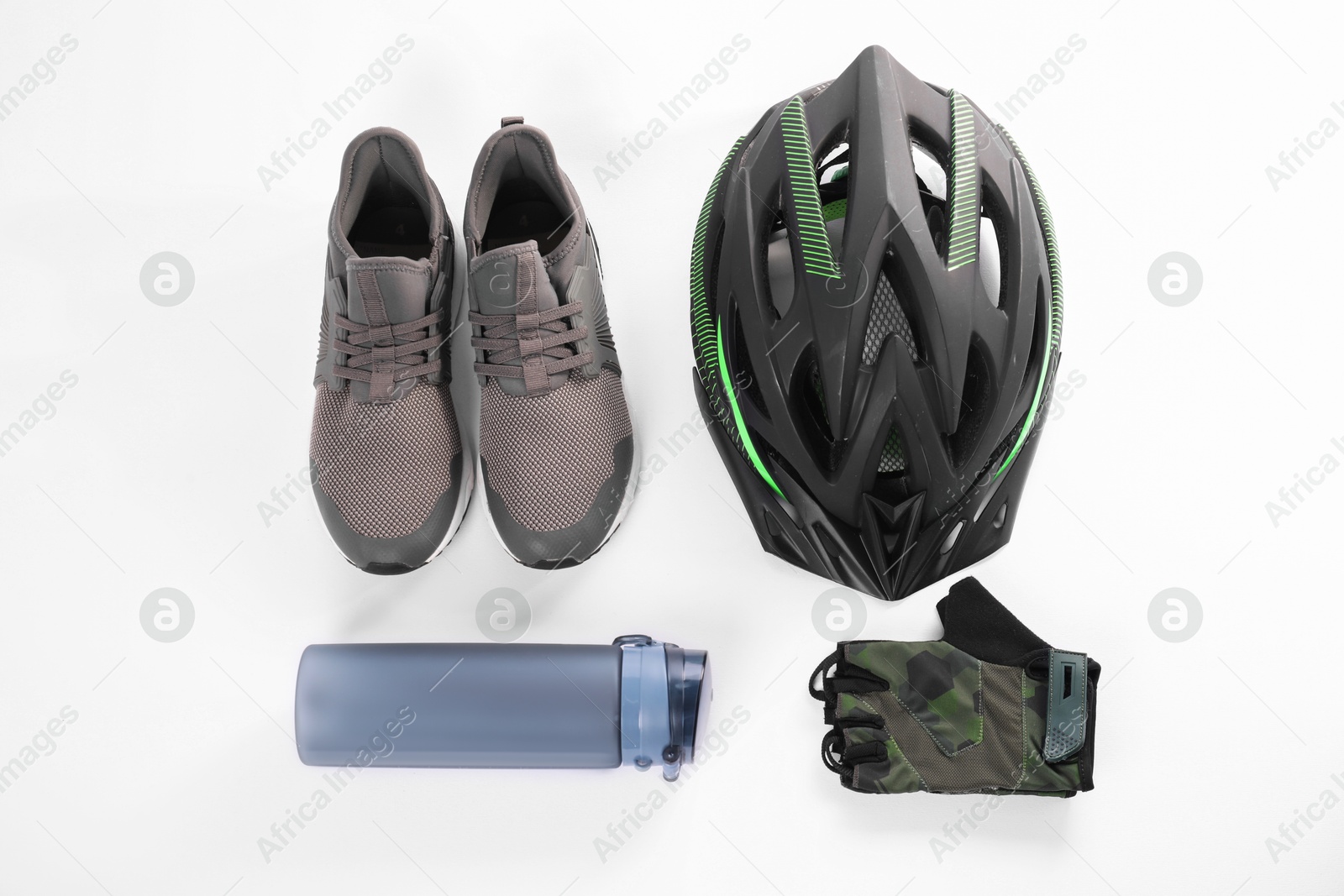 Photo of Bicycle helmet, sneakers, thermo bottle and fingerless gloves on white background, flat lay