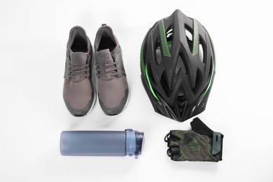 Bicycle helmet, sneakers, thermo bottle and fingerless gloves on white background, flat lay