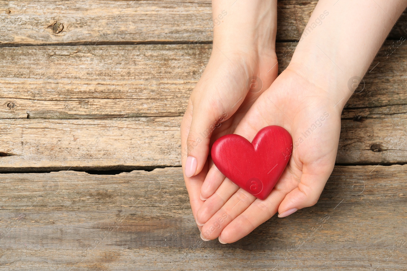 Photo of Woman with red decorative heart at wooden table, top view. Space for text