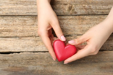 Photo of Woman with red decorative heart at wooden table, top view. Space for text