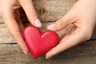 Photo of Woman with red decorative heart at wooden table, top view