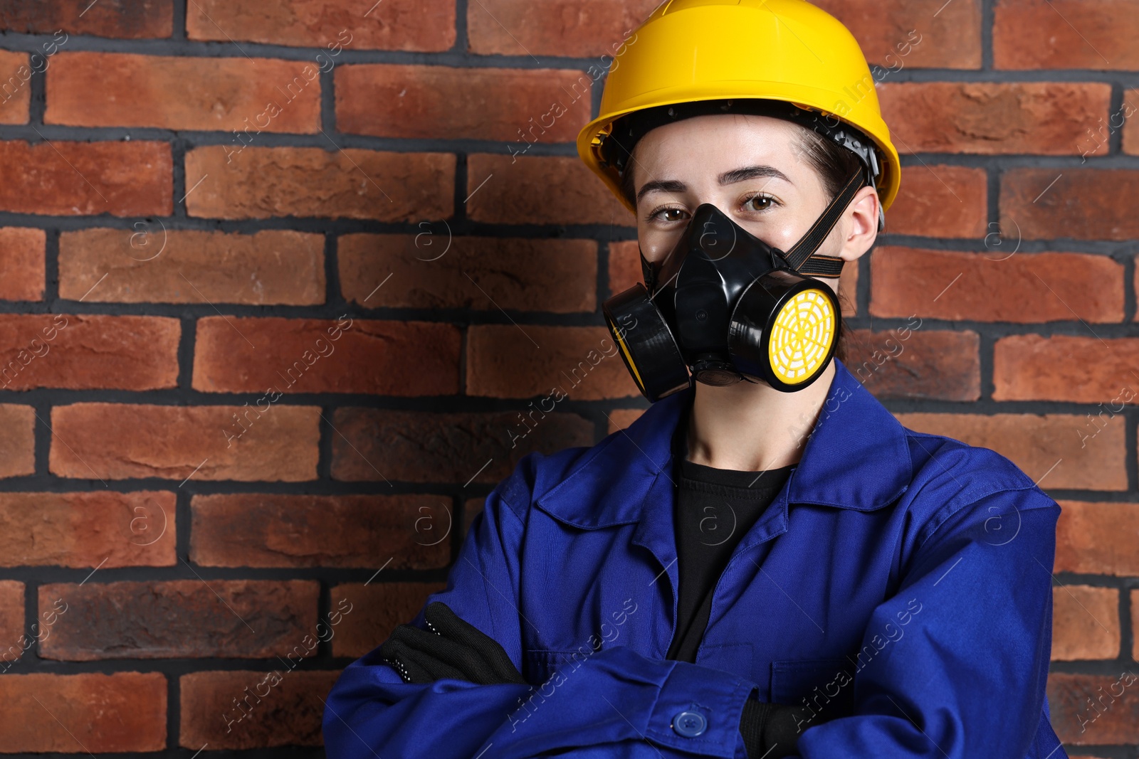 Photo of Worker in respirator and helmet near brick wall. Space for text