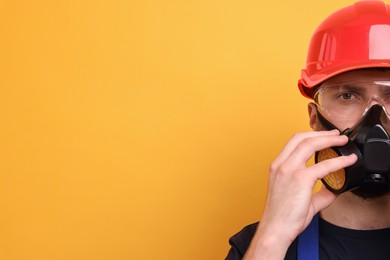 Photo of Man in respirator mask and hard hat on yellow background. Space for text