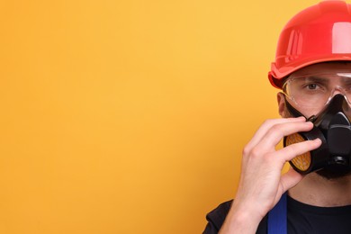 Man in respirator mask and hard hat on yellow background. Space for text