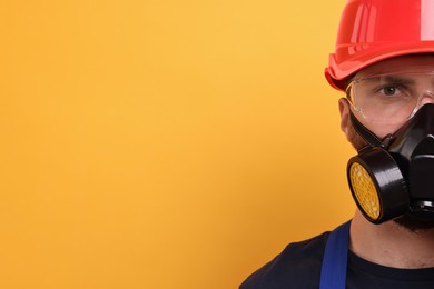 Man in respirator mask and hard hat on yellow background. Space for text